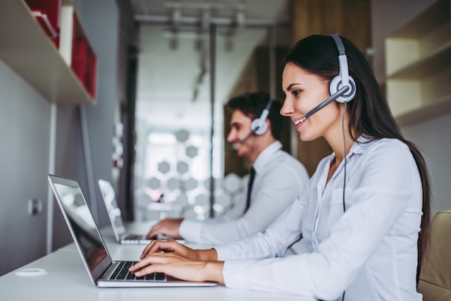 two workers using laptops and headsets to monitor security systems